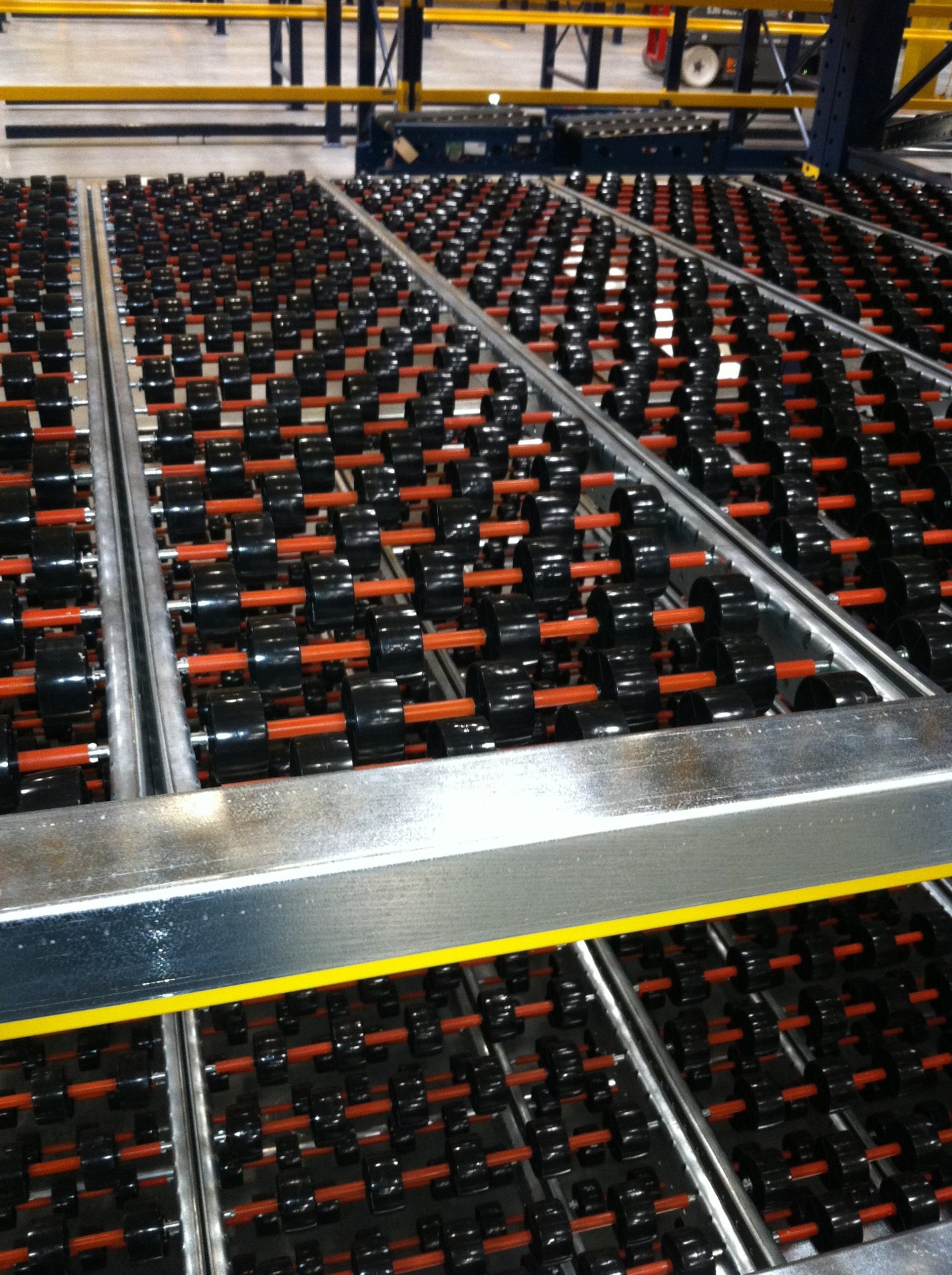 Carton flow rack with tilted wheel beds feeding cases to a pick face